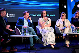 Trzy kobiety i dwóch mężczyzn siedzą na scenie na krzesłach i prowadzą panel dyskusyjny.