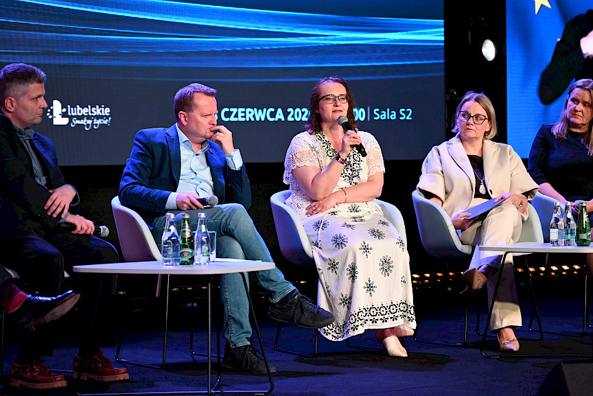 Trzy kobiety i dwóch mężczyzn siedzą na scenie na krzesłach i prowadzą panel dyskusyjny.