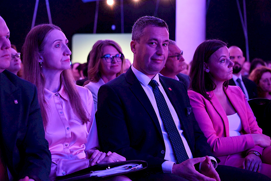 Członek Zarządu Marcin Szewczak siedzi na widowni wśród innych uczestników wydarzenia i patrzy prosto w obiektyw aparatu.