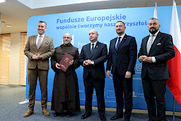 Przedstawiciele Zarządu Województwa Lubelskiego pozują do zdjęcia na ściance Funduszowej z beneficjentem projektu.