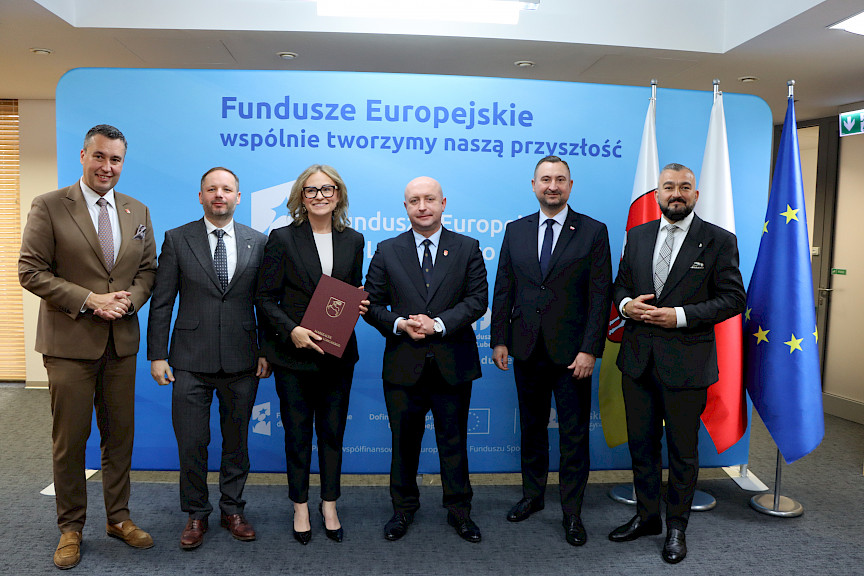 Przedstawiciele Zarządu Województwa Lubelskiego pozują do zdjęcia na ściance Funduszowej z beneficjentami projektu.