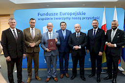 Przedstawiciele Zarządu Województwa Lubelskiego pozują do zdjęcia na ściance Funduszowej z beneficjentami projektu.