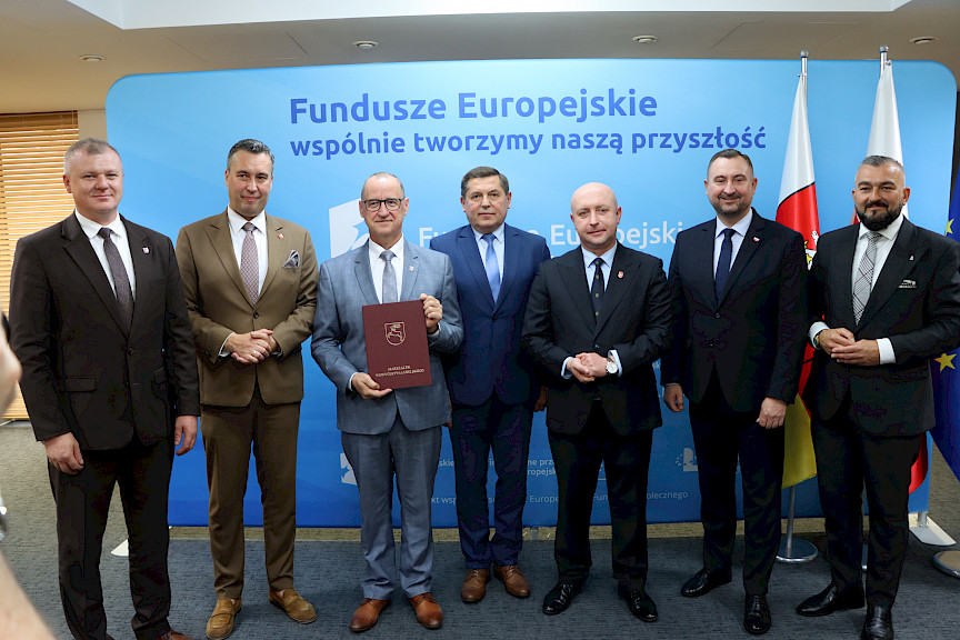 Przedstawiciele Zarządu Województwa Lubelskiego pozują do zdjęcia na ściance Funduszowej z beneficjentami projektu.