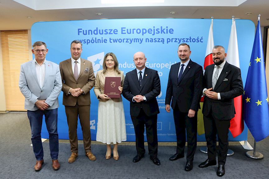 Przedstawiciele Zarządu Województwa Lubelskiego pozują do zdjęcia na ściance Funduszowej z beneficjentami projektu.