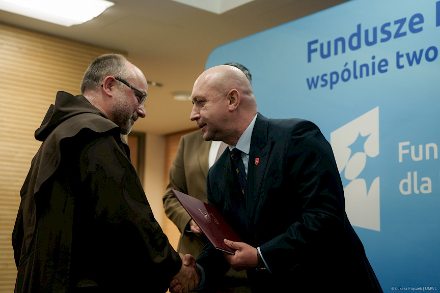 Wicemarszałek Województwa Lubelskiego Piotr Breś podaje rękę w ramach gratulacji beneficjentowi projektu, ujęcie z profilu.