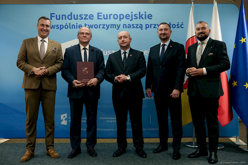 Przedstawiciele Zarządu Województwa Lubelskiego pozują do zdjęcia na ściance Funduszowej z beneficjentem projektu.