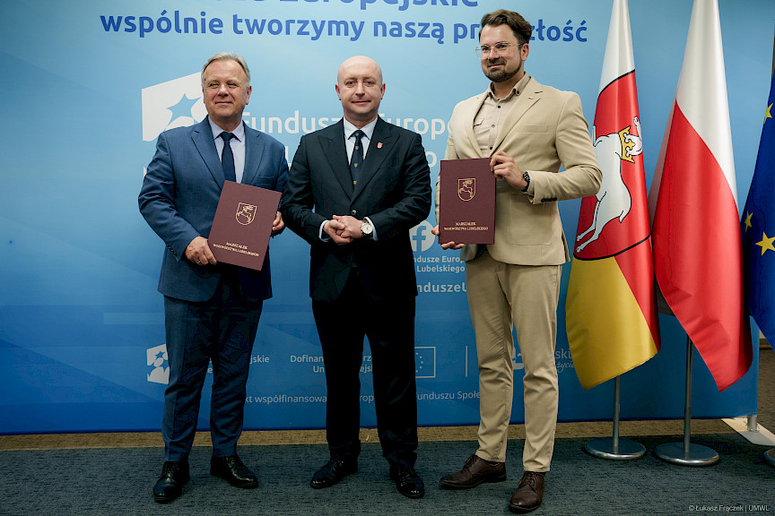 Wicemarszałek Województwa Lubelskiego Piotr Breś pozuje do zdjęcia na ściance Funduszowej z beneficjentami projektu.