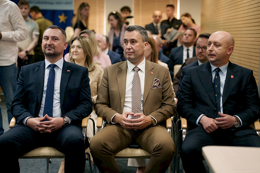 Dwóch Wicemarszałków Województwa Lubelskiego oraz Członek Zarządu siedzą obok siebie na krzesłach na widowni.