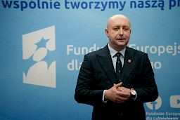 Wicemarszałek Województwa Lubelskiego Piotr Breś stoi na tle ścianki Funduszowej.