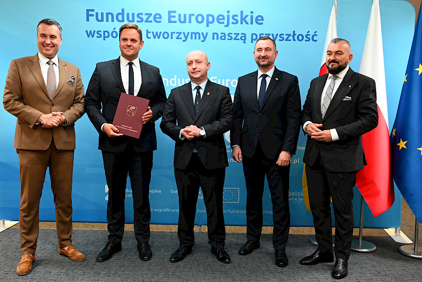 Przedstawiciele Zarządu Województwa Lubelskiego pozują do zdjęcia na ściance Funduszowej z beneficjentami projektu.