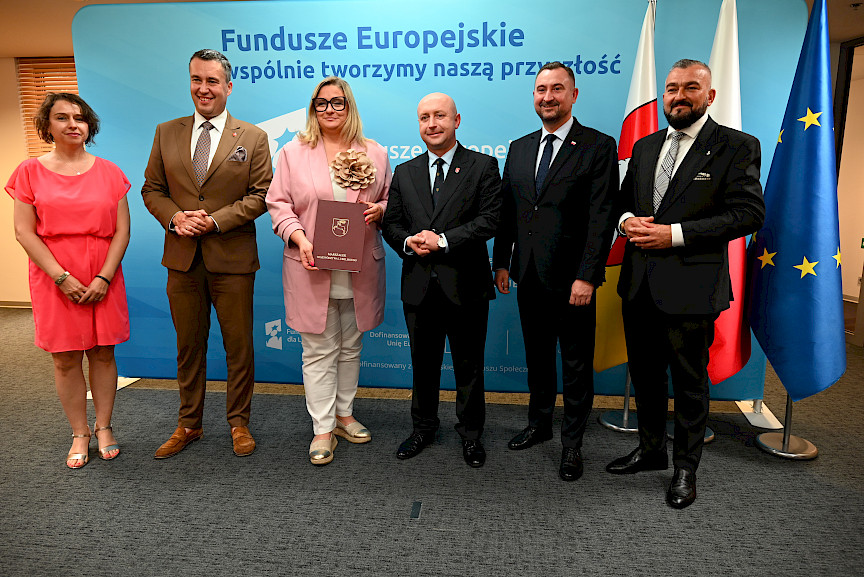 Przedstawiciele Zarządu Województwa Lubelskiego pozują do zdjęcia na ściance Funduszowej z beneficjentami projektu.