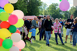 Na pierwszym planie po lewej kolorowe balony, w tle tłum ludzi na pikniku