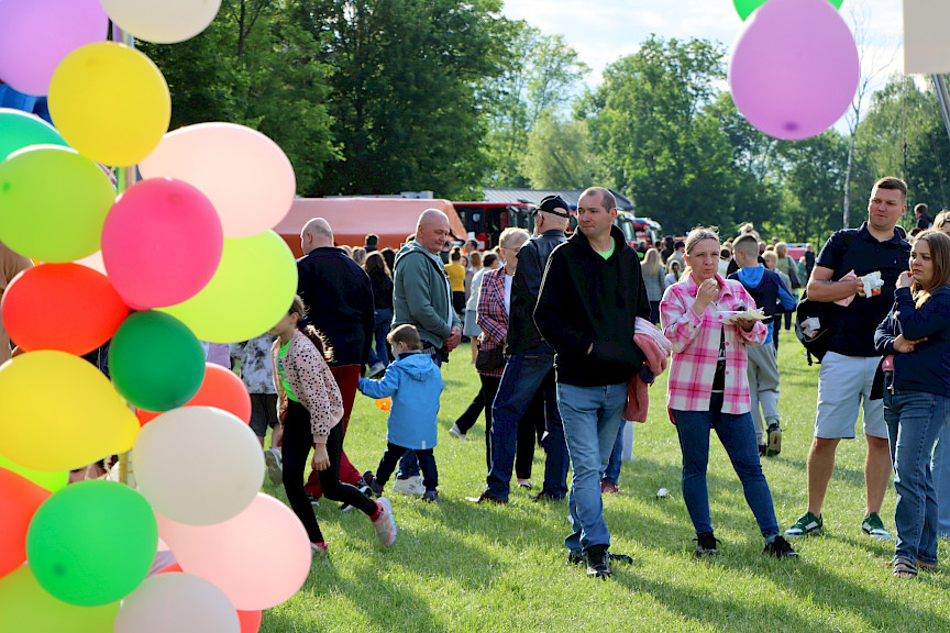 Na pierwszym planie po lewej kolorowe balony, w tle tłum ludzi na pikniku