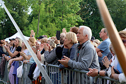 Tłum ludzi przed barierką oglądających koncert