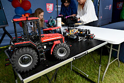 Model traktora z klocków na stoisku, w tle kobieta