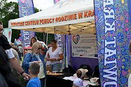 Stoisko Powiatowego Centrum Pomocy Rodzinie w Kraśniku, w środku panie, przed stoiskiem chłopiec