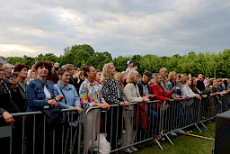 Tłum ludzi stojących przed barierką słuchający koncertu