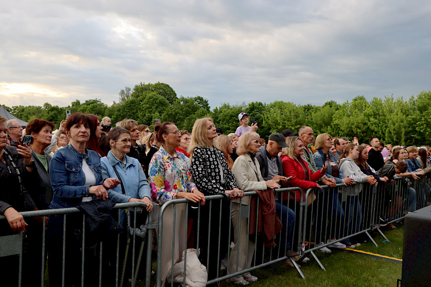 Tłum ludzi stojących przed barierką słuchający koncertu