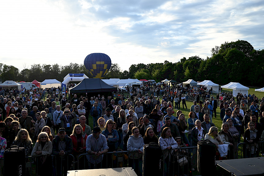 Tłum ludzi przed sceną, w tle balon na uwięzi i stoiska