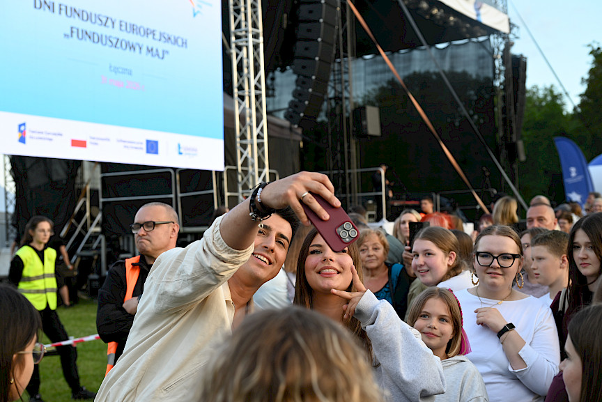 Filip Lato robiący sobie zdjęcie z fankami przy scenie, w tle tłum
