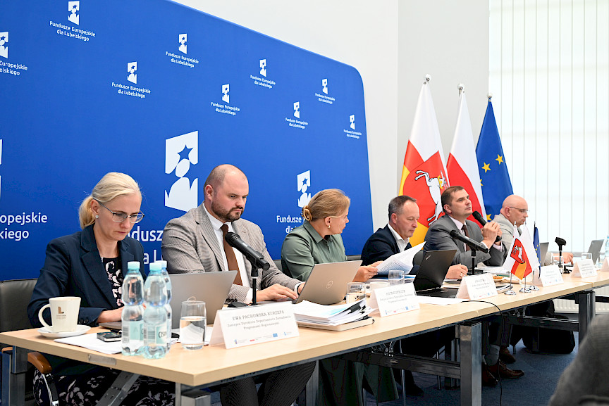 Dyrekcja Departamentu Zarządzania Programami Regionalnymi oraz przedstawiciele Departamentu Europejskiego Funduszu Rozwoju Regionalnego, Europejskiego Funduszu Społecznego siedzą za stołem.
