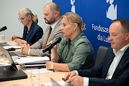 Dyrektor Anna Brzyska wypowiada się do mikrofonu, obok niej siedzi inni członkowie komisji.