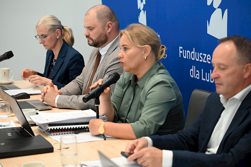 Dyrektor Anna Brzyska wypowiada się do mikrofonu, obok niej siedzi inni członkowie komisji.