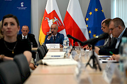 Widok z daleka na Dyrektora Lubelskiej Agencji Wspierania Przedsiębiorczości wypowiadająca się do mikrofonu. Bliżej widoczni są inni uczestnicy siedzący na sali.
