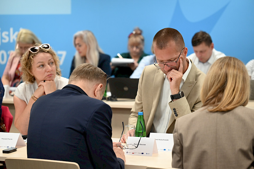 Ujęcie na uczestników posiedzenia siedzących za stołem.