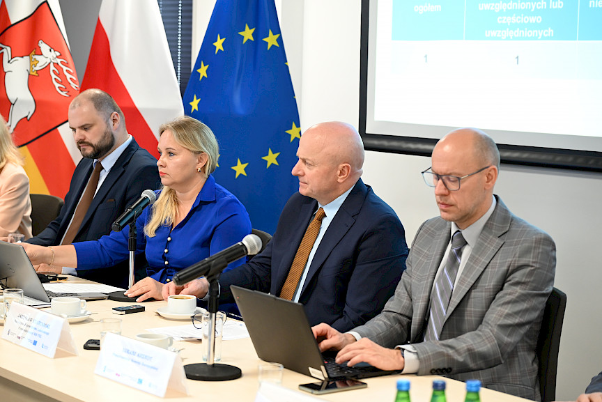 Dyrekcja Departamentu Zarządzania Programami Regionalnymi siedzą za stołem, obok siedzi Marszałek Województwa Lubelskiego Jarosław Stawiarski oraz mężczyzna w okularach notujący w laptopie.