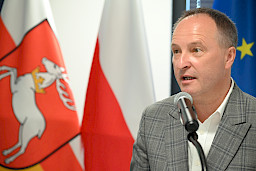 Ujęcie twarzy z bliska mężczyzny wypowiadającego się do mikrofonu.