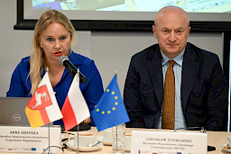 Dyrektor Departamentu Zarządzania Programami Regionalnymi Anna Brzyska wypowiada się do mikrofonu. Obok niej siedzi Marszałek Jarosław Stawiarski. Ujęcie na wprost twarzy z bliska.