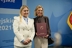 Dyrektor Departamentu Zarządzania Programami Regionalnymi Anna Brzyska stoi z beneficjentką projektu. Obie uśmiechają się szeroko.