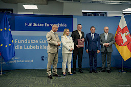 Marszałek Województwa Lubelskiego Jarosław Stawiarski, Dyrektor Anna Brzyska oraz Dyrektor LAWP Marek Neckier ustawieni są do zdjęcia z beneficjentem projektu.