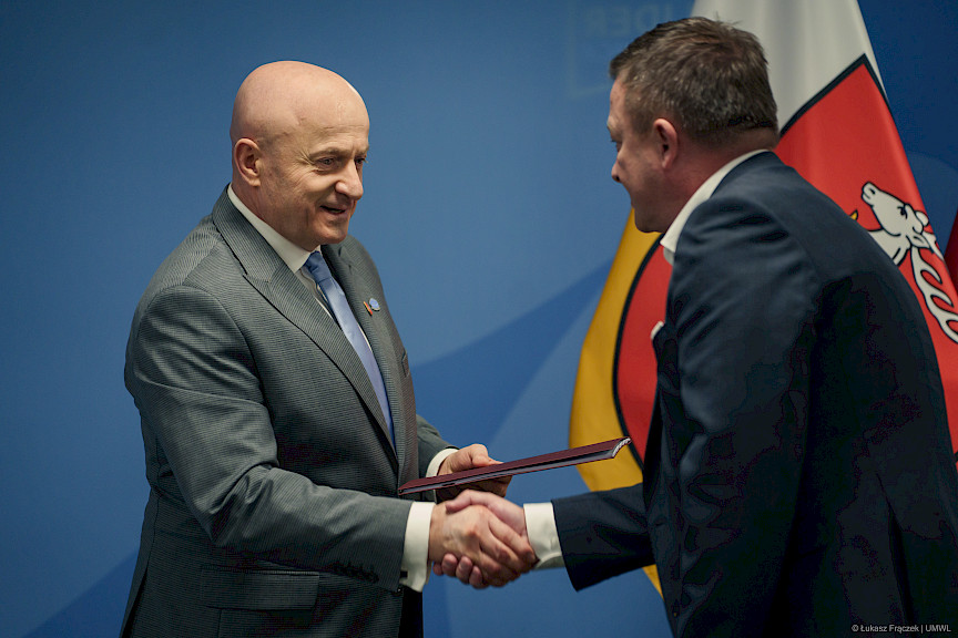 Marszałek Województwa Lubelskiego Jarosław Stawiarski podaje rękę w ramach gratulacji beneficjentowi projektu.