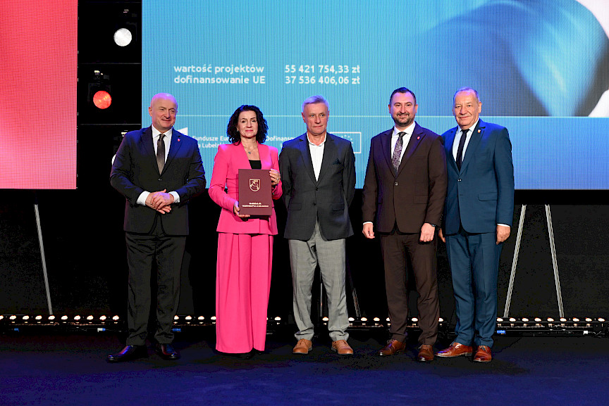 Marszałek Województwa Lubelskiego Jarosław Stawiarski oraz Wicemarszałek Marek Wojciechowski stoją z beneficjentami projektu, kobietą oraz mężczyzną.