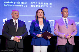 Marszałek Województwa Lubelskiego Jarosław Stawiarski z Członkiem Zarządu Marcinem Szewczakiem stoją z beneficjentką projektu.