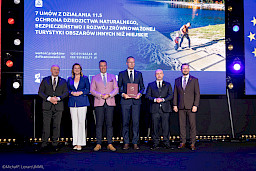 Zdjęcie Zarządu Województwa Lubelskiego z beneficjentem projektu, który trzyma w rękach bordową teczkę z umową.