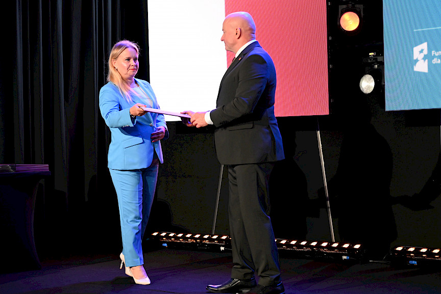 Dyrektor Departamentu Zarządzania Programami Regionalnymi Anna Brzyska podaje teczkę z umową Marszałkowi Jarosławowi Stawiarskiemu.