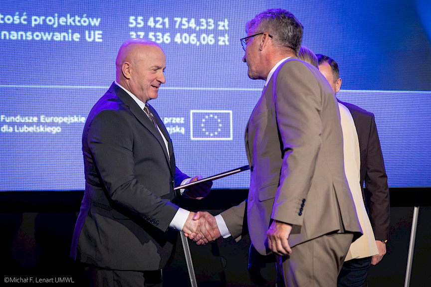 Marszałek Województwa Lubelskiego Jarosław Stawiarski podaje rękę beneficjentowi projektu w ramach gratulacji.