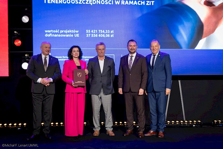 Marszałek Województwa Lubelskiego Jarosław Stawiarski z Wicemarszałkiem Markiem Wojciechowskim stoją z beneficjentami projektu.