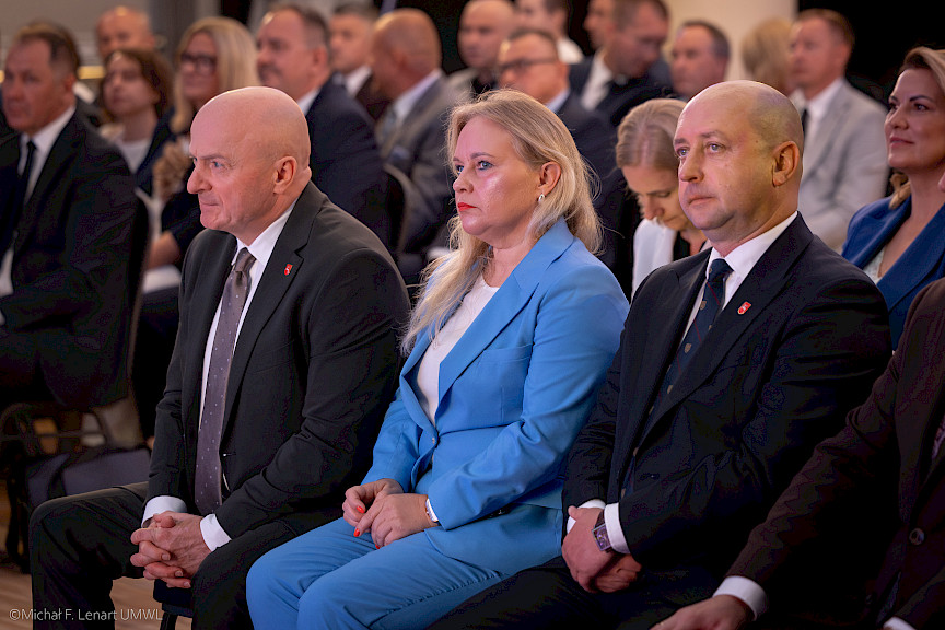 Marszałek Województwa Lubelskiego Jarosław Stawiarski siedzi obok Dyrektor Anny Brzyskiej oraz Wicemarszałka Piotra Bresia. W tle widać siedzących na sali innych uczestników wydarzenia.