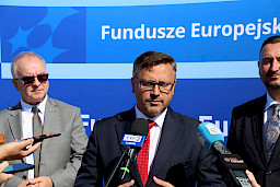 Prezes MPK Lublin Bogdan Kołciuk udziela wywiadu mediom do mikrofonów. Obok niego stoi Wicemarszałek Marek Wojciechowski oraz inny mężczyzna.