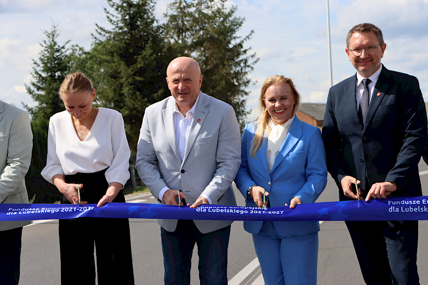 Marszałek Województwa Lubelskiego Jarosław Stawiarski, Dyrektor Departamentu Zarządzania Programami Regionalnymi Anna Brzyska, Radny Sejmiku Województwa Lubelskiego Paweł Kurek przecinają wspólnie taśmę otwierającą drogę. 