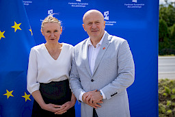 Marszałek Województwa Lubelskiego Jarosław Stawiarski pozuje do zdjęcia z kobietą. Za nimi stoi niebieska ścianka promująca  fundusze europejskie dla lubelskiego