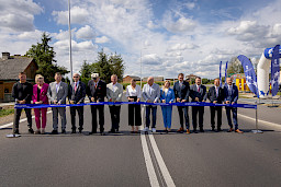 Ujęcie grupy osób ustawionych obok siebie, wszyscy trzymają nożyczki w ręku, są przed przecięciem symbolicznej wstęgi otwierającej drogę. Po środku stoi Marszałek Jarosław Stawiarski oraz Dyrektor Anna Brzyska.