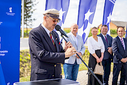 Burmistrz miasta urzędów wypowiada się do mikrofonu do uczestników wydarzenia. Obok stoi Marszałek Jarosław Stawiarski oraz inni uczestnicy wydarzenia.