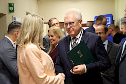 Dyrektor COZL Piotr Matej ściska rękę kobiecie podczas rozmowy. W koło na korytarzu widać inne osoby.
