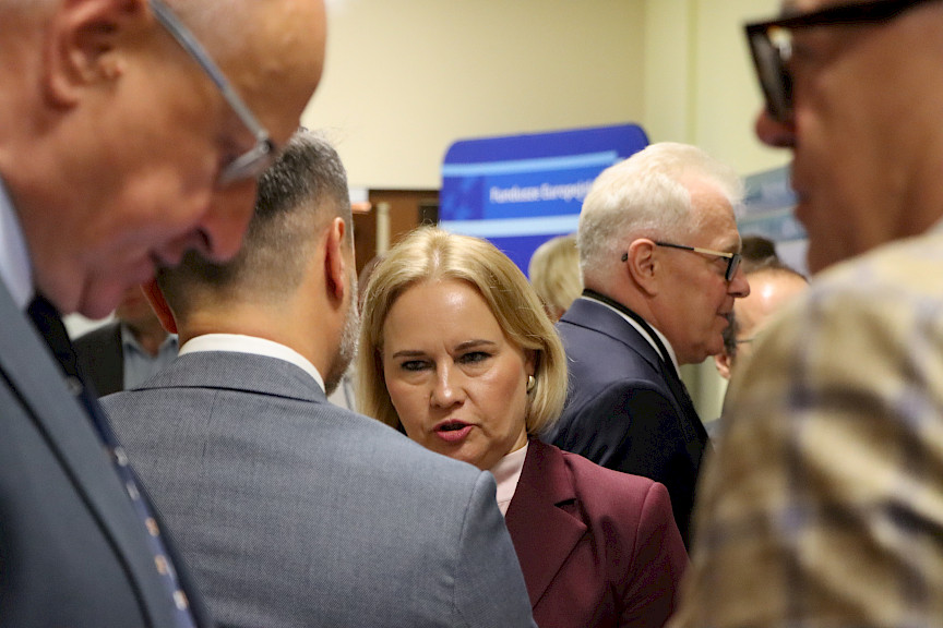 Ujęcie kilku osób rozmawiających ze sobą na korytarzu szpitala. Na wprost Dyrektor Departamentu Zarządzania Programami Regionalnymi Anna Brzyska.
