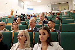Ujęcie od dołu na salę z siedzącymi uczestnikami wydarzenia.